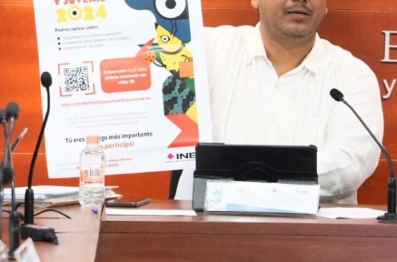 Hombre de camisa blanca sentado, sosteniendo cártel de la Consulta Infantil y Juvenil 2024