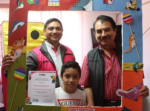 Dos hombres integrantes del INE y un niño posando para fotografía