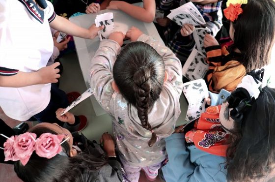 Niñas y niños integrando su voto a urna con ayuda de integrantes del INE