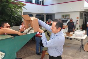 Hombre vaciando caja con credenciales a máquina para su destrucción