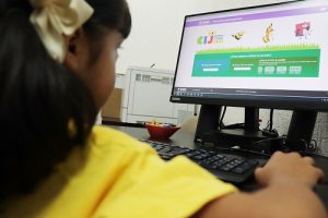 Niña utilizando computadora mientras visita página web de Consulta Infantil y Juvenil