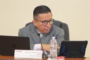 Hombre de lentes sentado detrás de mesa con tablet