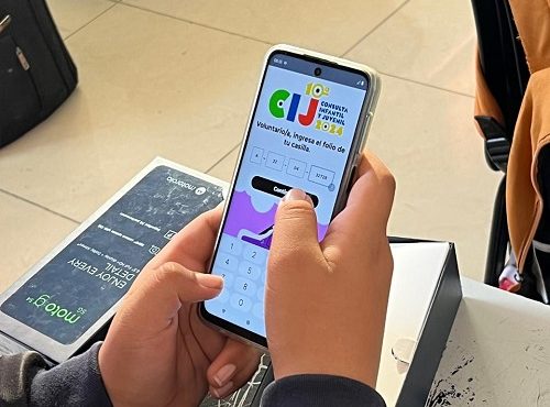Manos de joven utilizando celular para ingresar a página de la Consulta Infantil y Juvenil 2024