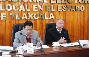 Dos hombres sentados detrás de escritorio, durante sesión