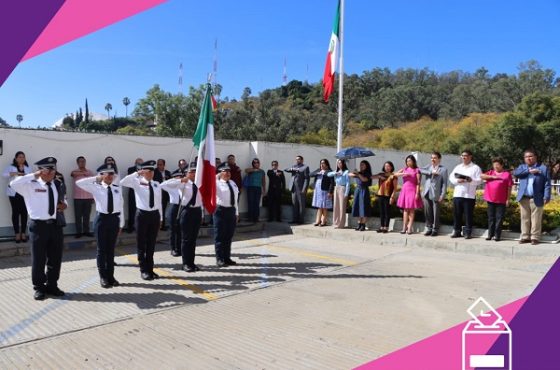 Escolta marchando con bandera nacional frente a integrantes del INE