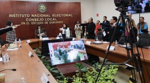 Integrantes del INE de pie, algunos estirando su brazo derecho