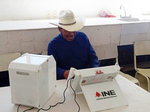 Hombre de sombrero vaquero, sentado utilizando urna electrónica