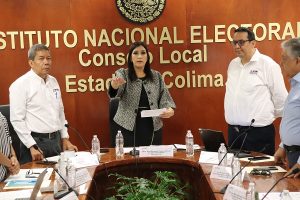 Dos hombres y una mujer de pie durante sesión del consejo local
