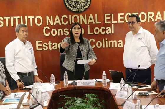 Dos hombres y una mujer de pie durante sesión del consejo local