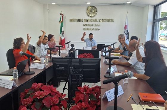 Integrantes del INE sentados levantando su mano