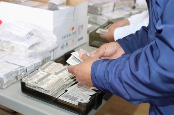 manos de un hombre de camisa azul marino, sosteniendo un paquete de credenciales para votar