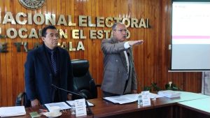Dos hombres de pie, uno de ellos estirando su brazo derecho