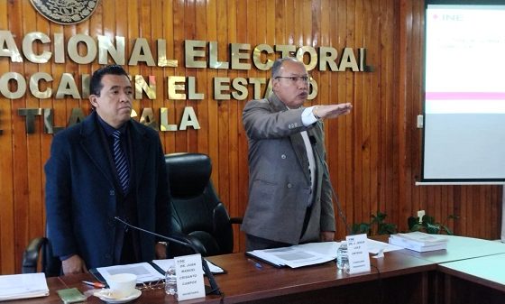 Dos hombres de pie, uno de ellos estirando su brazo derecho