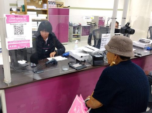 Una mujer atendiendo a otra mujer en un módulo del INE