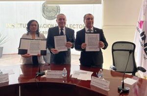 Tres personas de pie mostrando un documento