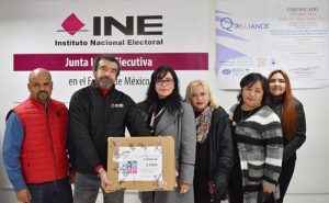 Personas de pie mostrando una caja que contienen examenes