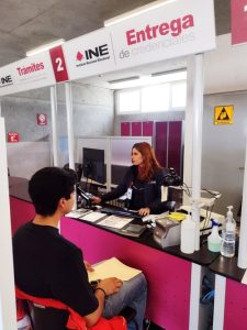 Mujer atendiendo en Módulo del INE a un hombre