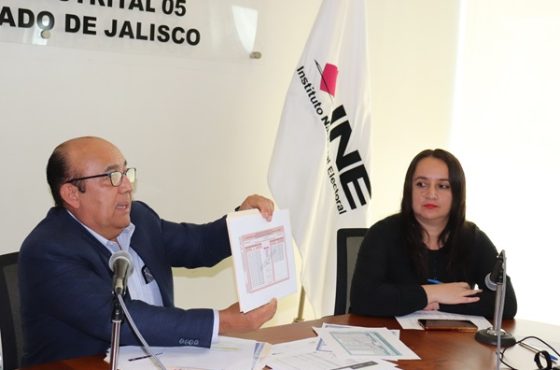 Dos personas sentadas, uno de ellos hombre muestra un documento