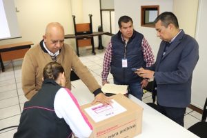 Personas entregando cajas que contienen exámenes