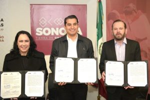 Una mujer y dos hombre vestidos de negro, con un diploma cada uno en las manos