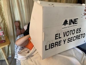 Persona en cama realizando su voto en mampara del INE