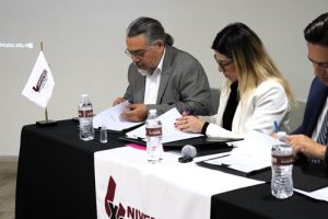 dos personas sentadas firmando el documento