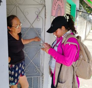 Trabajadora del INE Yucatán platicando con una señora en su domicilio