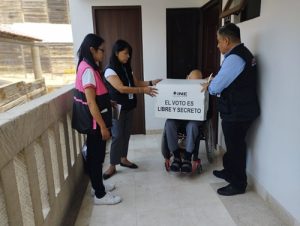 Tres personas del INE platicando con una persona en silla de ruedas