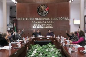 varias personas votando a mano alzada en reunión del INE en Chihuahua