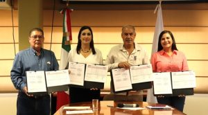 cuatro personas de pie sosteniendo el convenio firmado