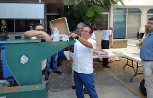 Una persona echando credenciales para votar caducas a una trituradora