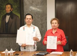 dos personas de pie mostrando los convenios firmados