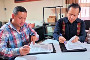 Dos personas sentadas firmando el convenio