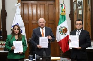 Tres personas de pie mostrando el Convenio firmado