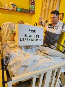 Persona de la tercera edad emitiendo su voto postrado en su cama