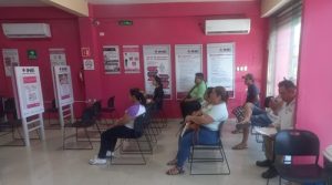 Personas sentadas esperando ser atendidas en un módulo del INE