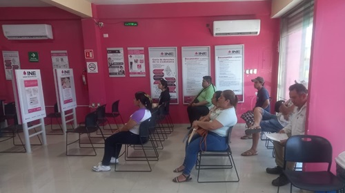 Personas sentadas esperando ser atendidas en un módulo del INE