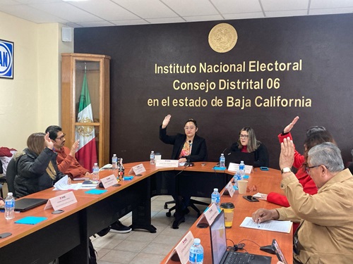 Personas en el salón del Consejo Local en Baja California votando a mano alzada