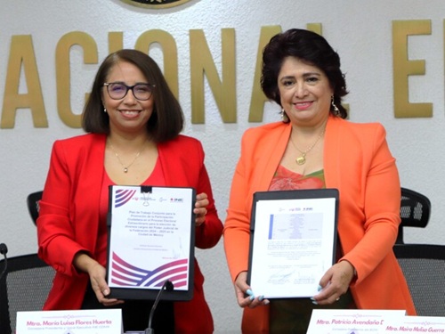 Dos mujeres vestidas de color naranja sosteniendo dos documentos
