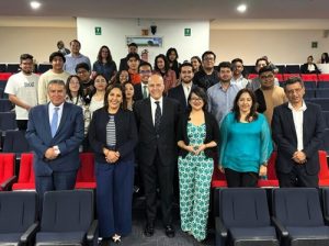 Mujeres y hombres de pie en un auditorio tomándose una foto