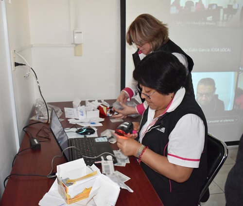 Dos mujeres realizando cortes laterales en credenciales para votar