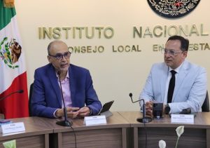 Dos hombres sentados frente a una mesa con micrófonos