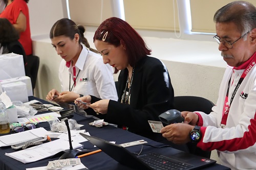 Dos mujeres y un hombre haciendo cortes laterales a credenciales para votar