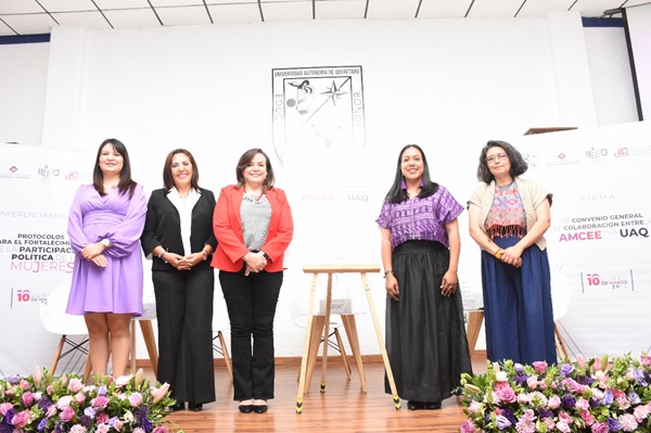 cinco mujeres de pie, sonriendo y posando para la fotografía