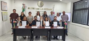 Personas sentadas y de pie, mostrando un documento
