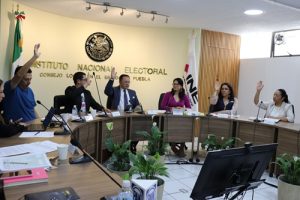 Personas votando a mano alzada en el Consejo Local del INE Puebla