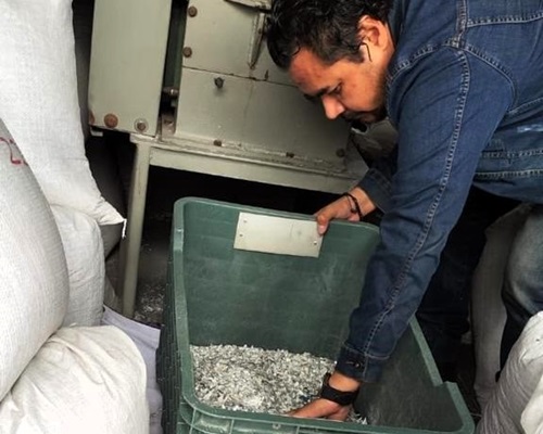 Una persona levantando una caja de plástico con pedacería de las credenciales