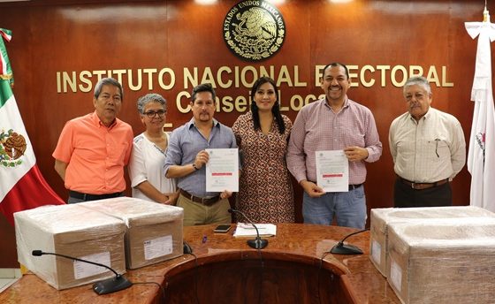 seis personas de pie sosteniendo unos documentos