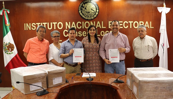 seis personas de pie sosteniendo unos documentos