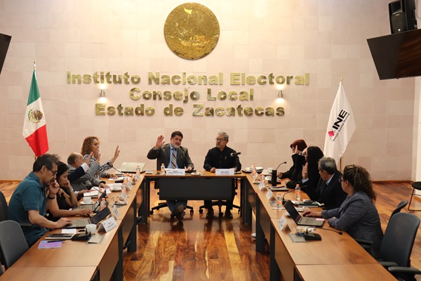 integrantes de consejo local sentados y votando a mano alzada